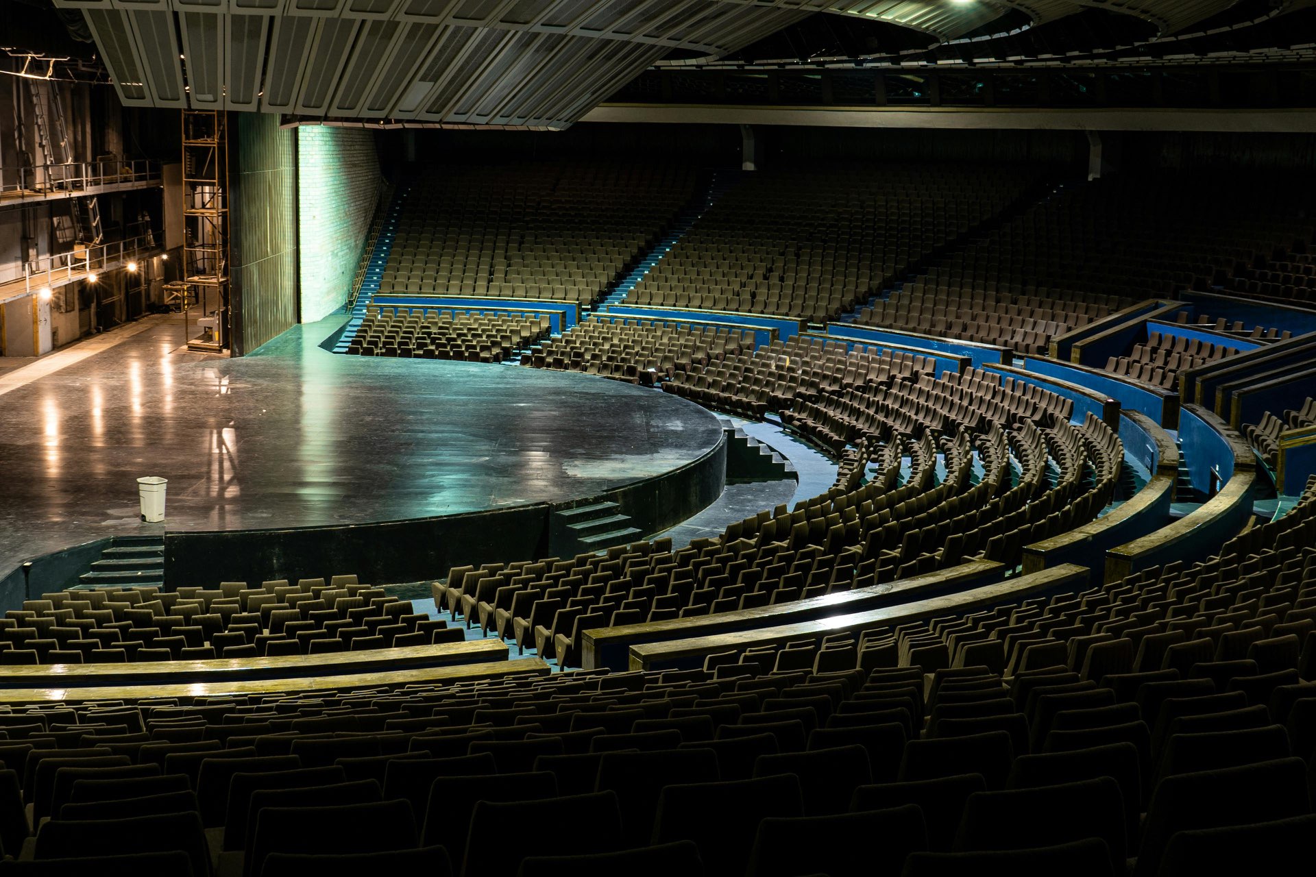 Interior of a large performance theater showing the empty stage, seating bowl, and dramatic lighting